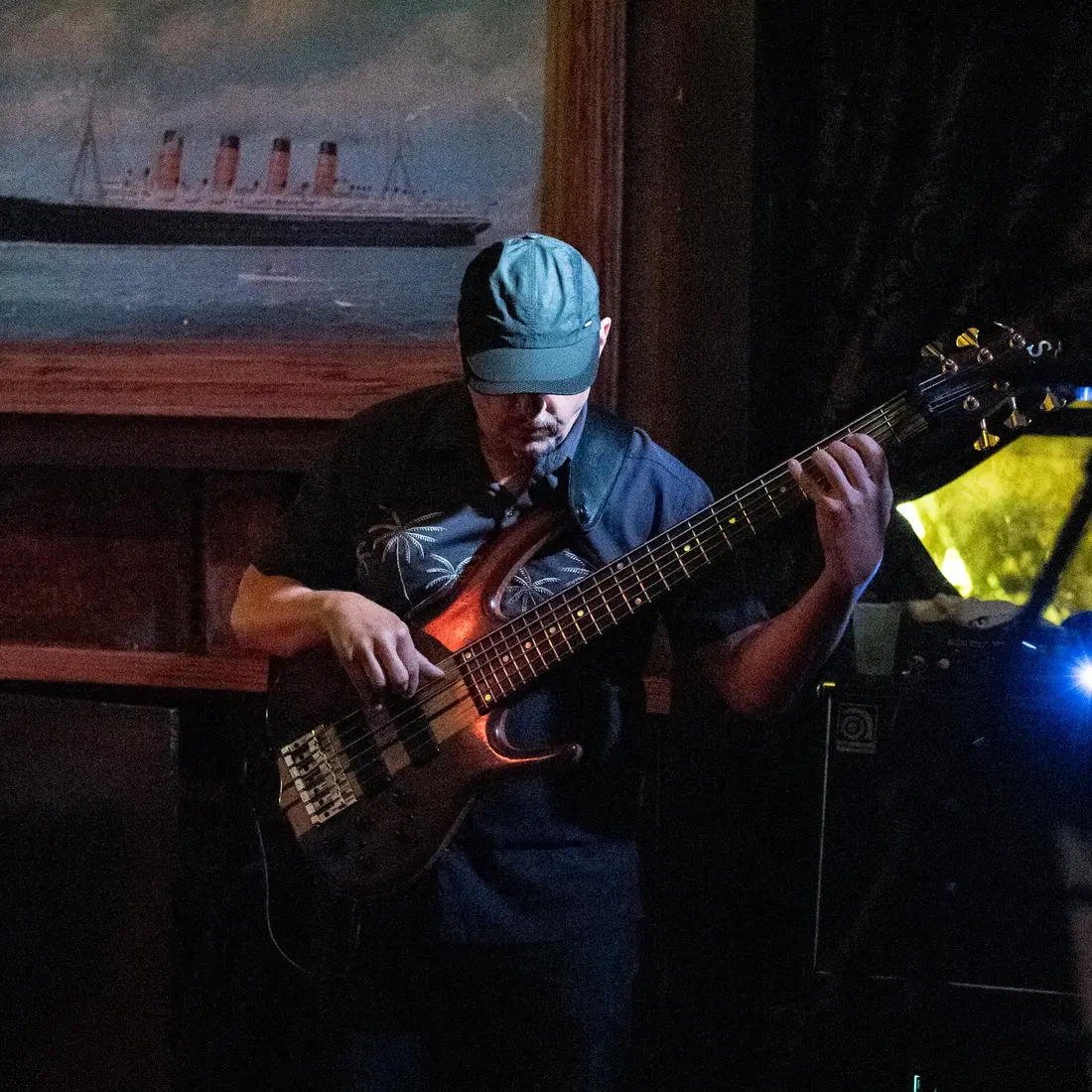 Russ Rodgers playing bass on a warm wood-panelled stage