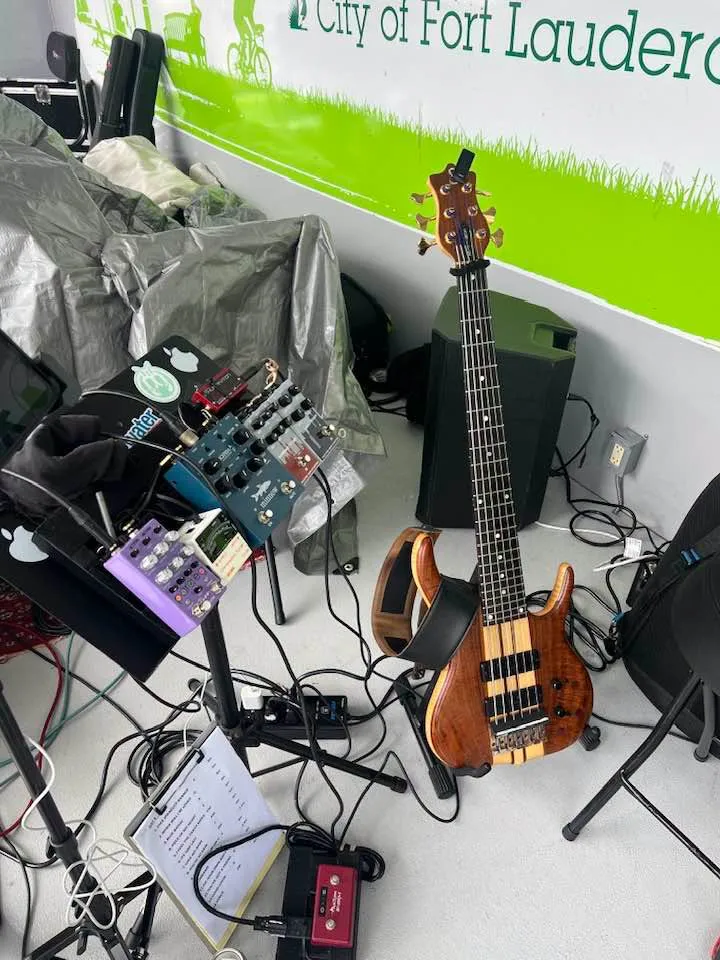 Russ's full stage rig — bass on a stand, pedalboard, and cases