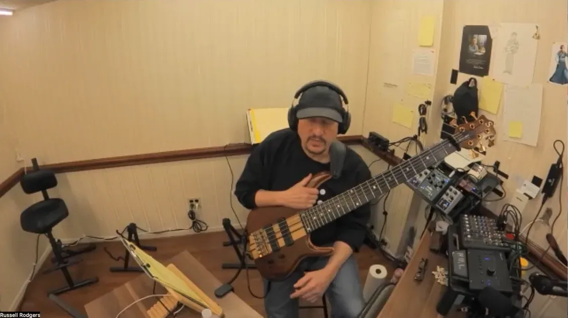 Russ teaching on a Zoom call, bass in hand in his studio